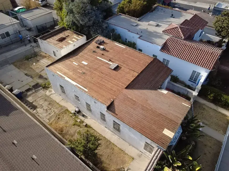 Aerial view of a weathered low-slope roof on a stucco house