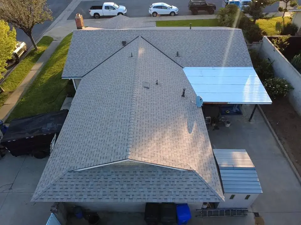 Aerial view of a new gray shingle roof and a flat patio cover