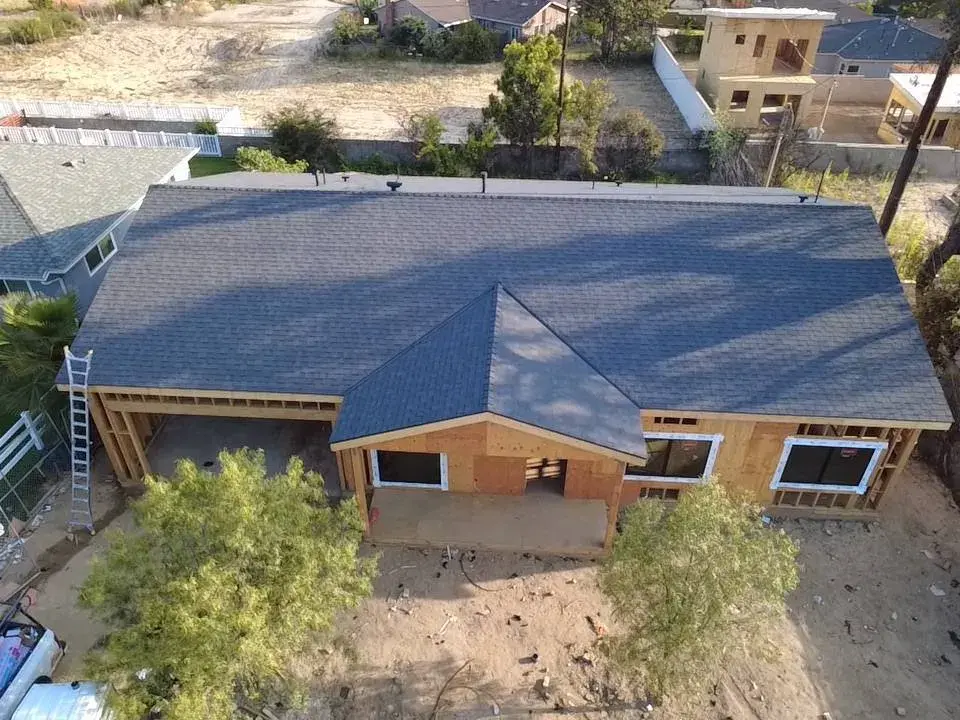 Aerial view of a new dark shingle roof on a home with a wood porch