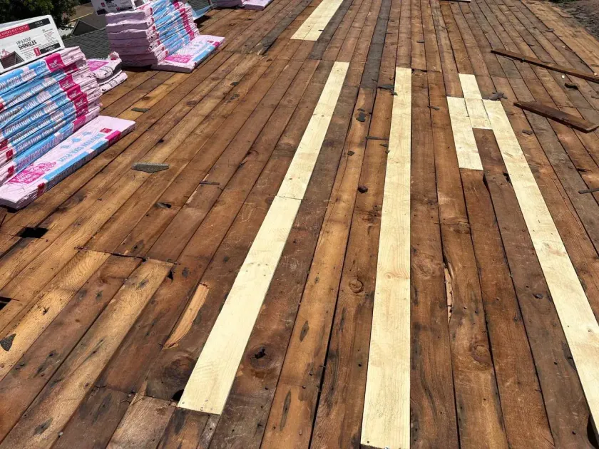 Wood plank roof deck with new plywood strips during a re-roof