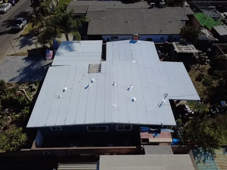 Aerial view of a flat roof covered in a new white membrane with sealed vent pipes