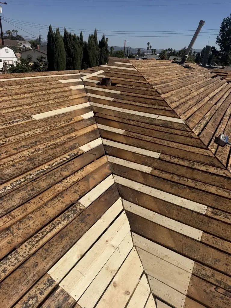 Hip roof stripped to the deck with new boards laid along the hip lines