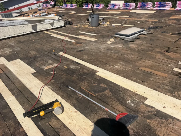 Old roof stripped to the plank deck with new boards patched in, a nail gun and a skylight opening