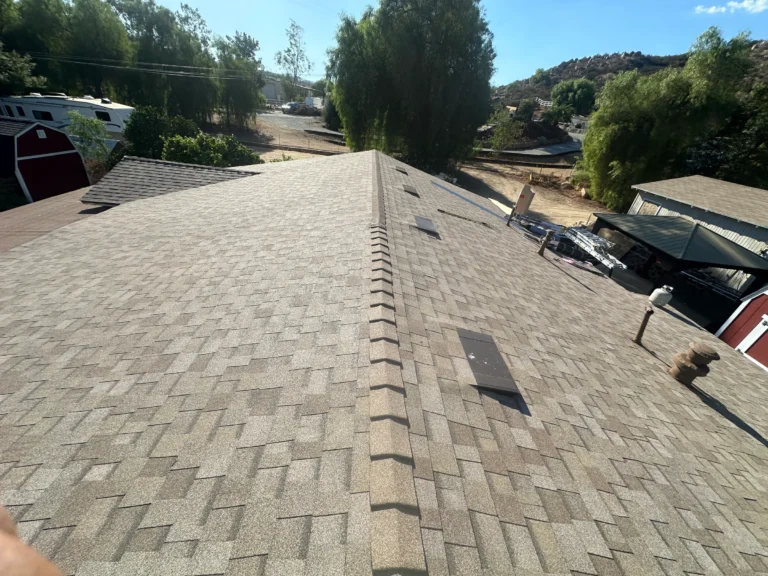 New tan shingle roof with a ridge cap and skylights, a red barn and a hillside behind