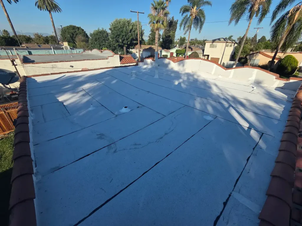 Flat roof covered in white membrane sheets with overlapping seams, inside a parapet wall